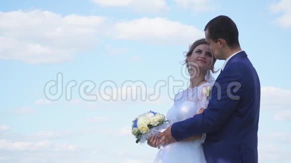 在云彩的背景下温柔地摆姿势的新娘和新郎视频的预览图