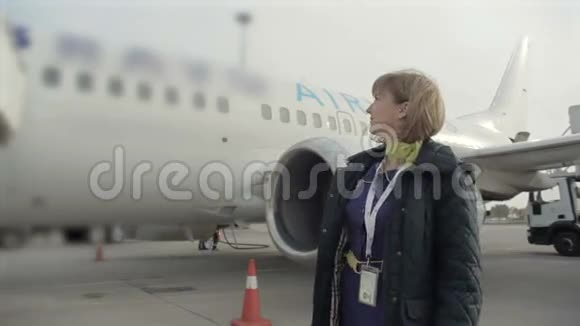 年轻微笑的空姐站在飞机的背景上视频的预览图