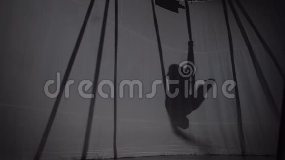 一个女孩进行空中瑜伽复杂练习的剪影视频的预览图