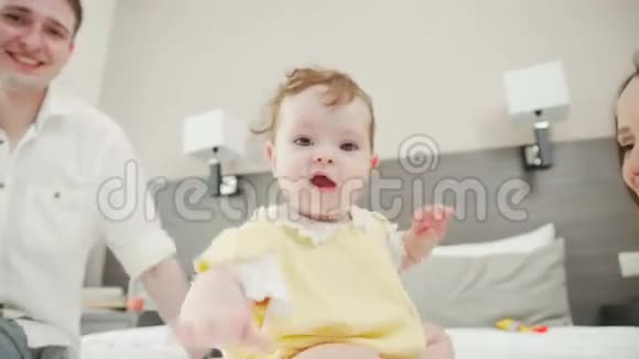 迷人的婴儿在床上爬行父母照顾他们的女儿视频的预览图