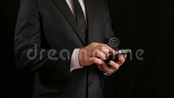 概念数字在线生活和社交网络一个穿着黑色西装系着领带的商人用智能手机看视频的预览图