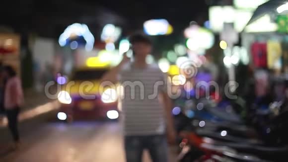 在城市里年轻的帅哥在晚上用手机说话车水马龙视频的预览图