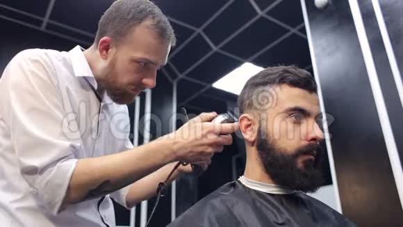 理发师给一个留着胡子的英俊男子剪羊毛视频的预览图
