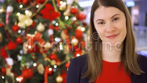 圣诞树上装饰的年轻女子的肖像漂亮的女人站着微笑视频的预览图