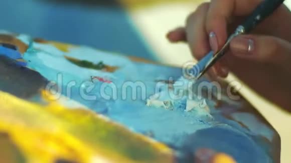 有画笔的女性手女人在画家调色板上混合油画视频的预览图
