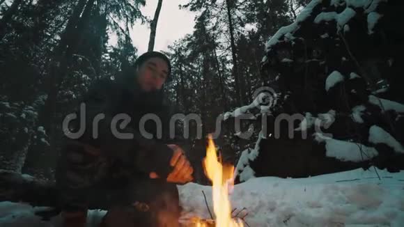 坐在森林里篝火前的旅行者试图取暖视频的预览图