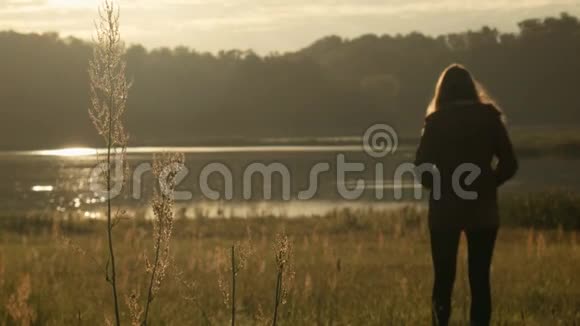 日出时站在湖边的年轻女子剪影视频的预览图