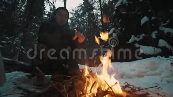 坐在森林里篝火前的旅行者试图取暖视频的预览图