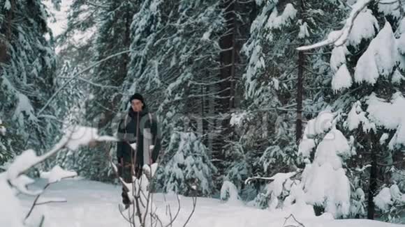 冬天的一天年轻的徒步旅行者走在森林覆盖的雪道上视频的预览图