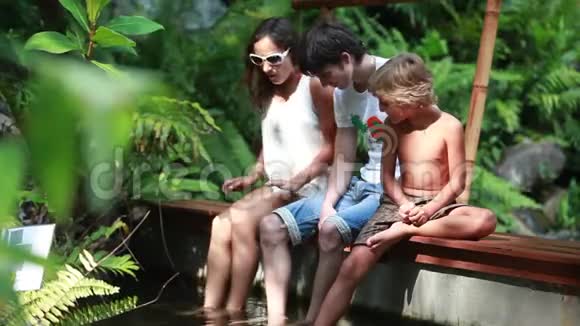 幸福的家庭在热带丛林的天然池塘里有一个鱼水疗中心1920x1080视频的预览图