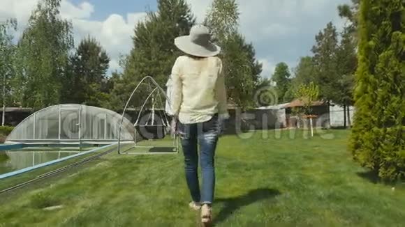 漂亮的女士走过花园里的草坪视频的预览图