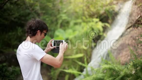 年轻人用美丽的瀑布背景拍照1920x1080视频的预览图