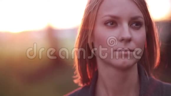 公园里年轻沉思的女人的肖像在夕阳的照耀下眺望远方特写视频的预览图