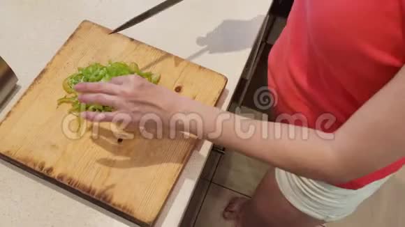 特写镜头女人在家里厨房的木板上切绿色的辣椒视频的预览图