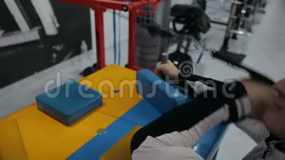 运动员肌肉健美运动员在健身房模拟器上训练二头肌视频的预览图