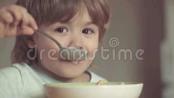 笑着可爱的小男孩坐在高椅上在厨房的背景下吃东西快乐的孩子可爱的孩子吃视频的预览图