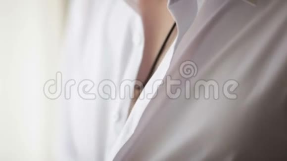 男人在白色衬衫上扣扣子视频的预览图