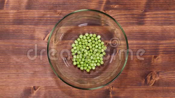 豌豆慢慢地在桌子上装满了一个玻璃碗视频的预览图