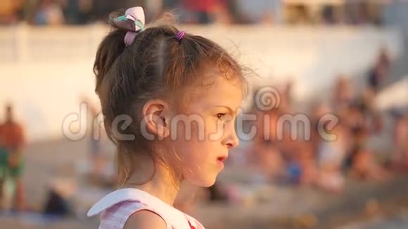 美丽的微笑的小女孩站在海滩上与人们在一起视频的预览图