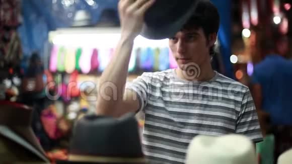 年轻男性买家在街头商店尝试新帽子和看镜子的肖像1920x1080视频的预览图