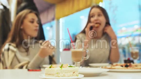 两个女学生的女朋友喝鸡尾酒在咖啡馆里聊天秋天冬天在前景蛋糕里视频的预览图