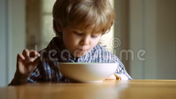 可爱的婴儿吃小男孩在厨房吃早餐快乐的小男孩勺子吃自己宝宝吃食物视频的预览图