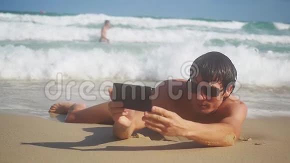 男游客手里拿着智能手机在海滨海滩上自拍暑假游客视频的预览图