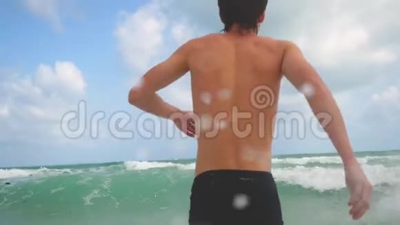 英俊的年轻人走进大海缓慢地拍打着波浪快乐暑假休息放松娱乐视频的预览图