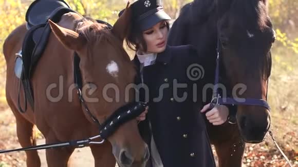 在温暖的秋天天气里活泼的小女孩带着两匹马在森林里散步视频的预览图