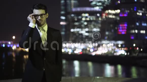 年轻的商人戴着眼镜晚上看城市风景视频的预览图