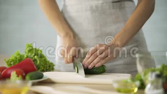 女厨师用小刀切新鲜黄瓜在木板上蔬菜视频的预览图