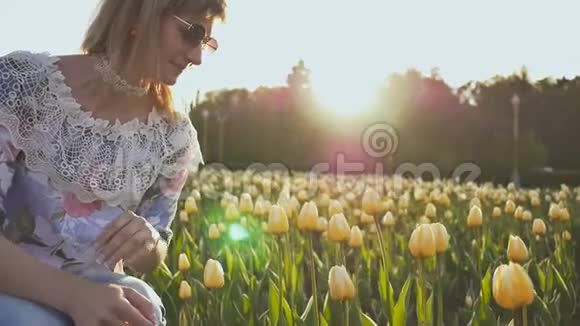 一个年轻的女孩在夏天的晚上触摸和享受五颜六色的郁金香视频的预览图