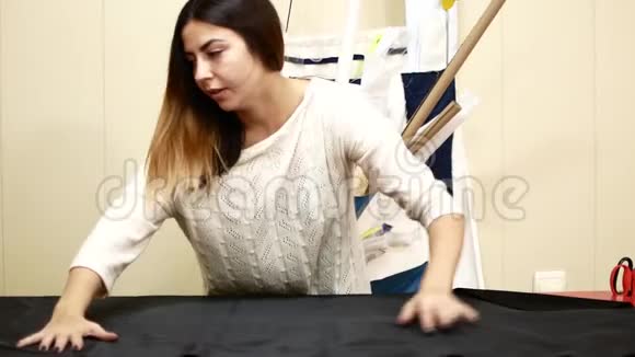 缝纫厂一个女人在一家裁缝公司工作女裁缝把布展开为图案视频的预览图