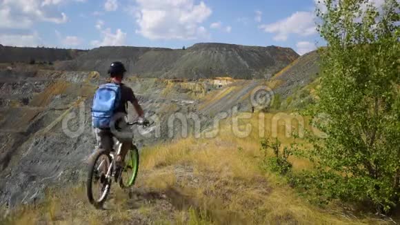 一个骑自行车的年轻人沿着峡谷的悬崖骑行视频的预览图