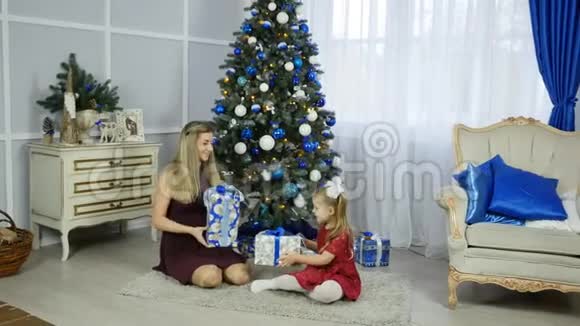 圣诞早晨一家人的母亲和孩子的女儿在圣诞树上带着礼物视频的预览图
