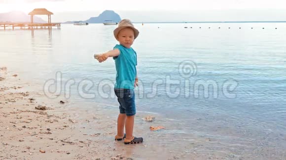 可爱的男孩把小石子扔进海里慢动作视频的预览图