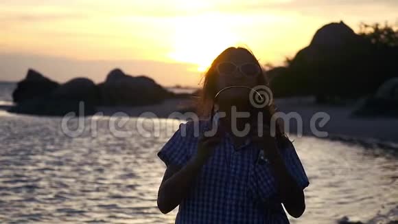 年轻女子戴着耳机在令人惊叹的日落时分在海滩上缓慢地听音乐1920x1080视频的预览图
