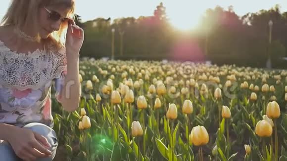 一个年轻的女孩在夏天的晚上触摸和享受五颜六色的郁金香视频的预览图