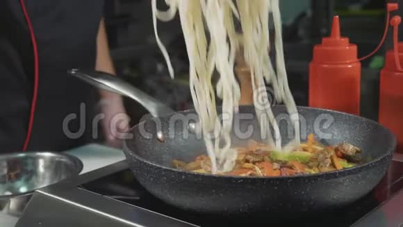 厨师把面条放在热煎锅上里面有各种蔬菜和肉视频的预览图