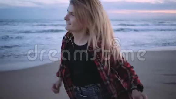日落或黄昏时分海滩上快乐的金发女孩视频的预览图