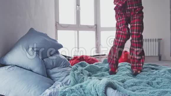 一个穿着睡衣的兴奋女孩的腿她在家里跳在她的特大床上慢动作3840x2160视频的预览图