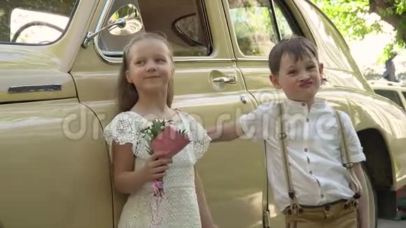 那个带着妹妹的小男孩摆着一辆米色的复古大轿车视频的预览图