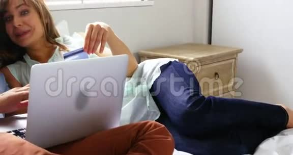 快乐的一对情侣躺在床上上网购物视频的预览图