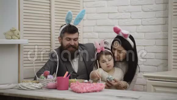 母亲父亲和女孩正在画复活节彩蛋幸福的家庭正在为复活节做准备可爱的小女孩视频的预览图