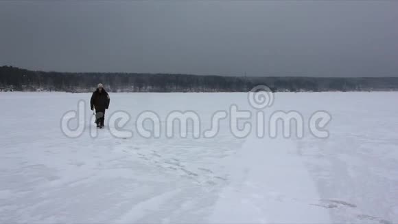 一个背着背包在冰冻的河面暴风雪中行走的人视频的预览图