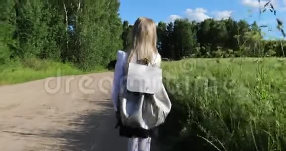 一个漂亮的小女孩在穿过田野的路上上学视频的预览图