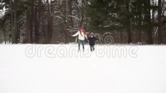 母亲和儿子在雪地里奔跑冬日美妙视频的预览图