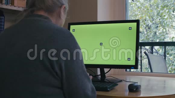高级女性在电脑上打绿色屏幕视频的预览图