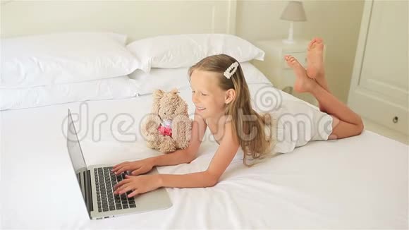 可爱的小女孩在笔记本电脑上做作业视频的预览图