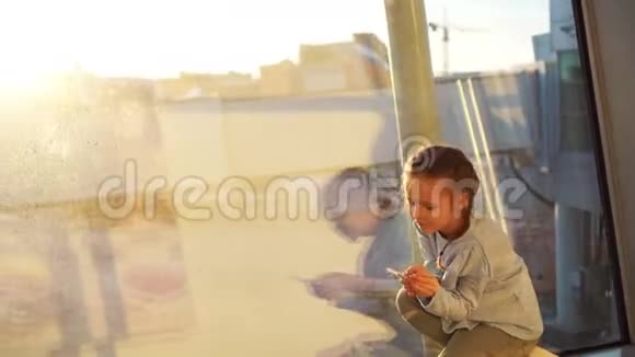 可爱的小女孩在机场大窗户附近玩小模型飞机玩具飞行和飞机的概念视频的预览图